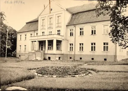 Widok Szkoły Podstawowej im. Karola Miarki w Kochanowicach od strony południowo-zachodniej z 15 czerwca 1974 roku. Po remoncie szkoły i najbliższego otoczenia w dolnym lewym rogu możemy zobaczyć odnaleziony głaz z wyrytą datą 3.V.1923